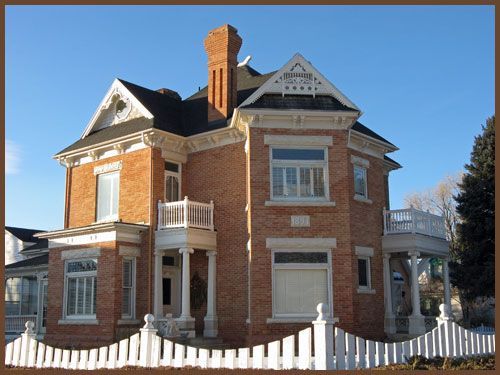 A large brick house with a white picket fence around it