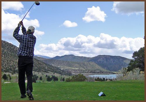 A man is swinging a golf club on a golf course