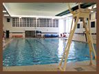 A large indoor swimming pool with a lifeguard tower in the background.
