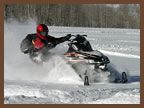 A man is riding a snowmobile through the snow.