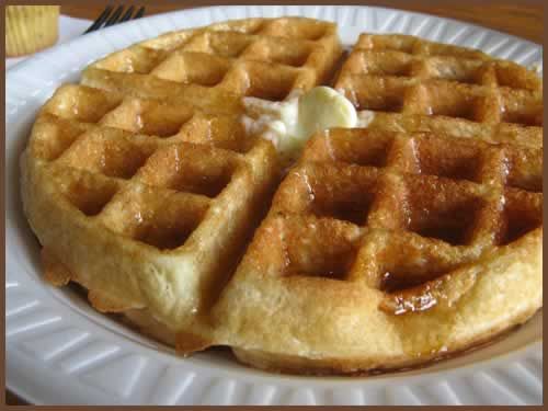 A waffle with butter and syrup on a white plate