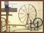 Two spinning wheels are sitting next to each other in a room.
