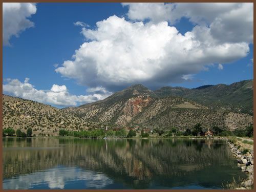 A lake with mountains in the background and clouds in the sky