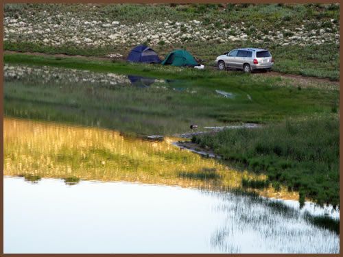 A car is parked on the side of a road next to a lake.