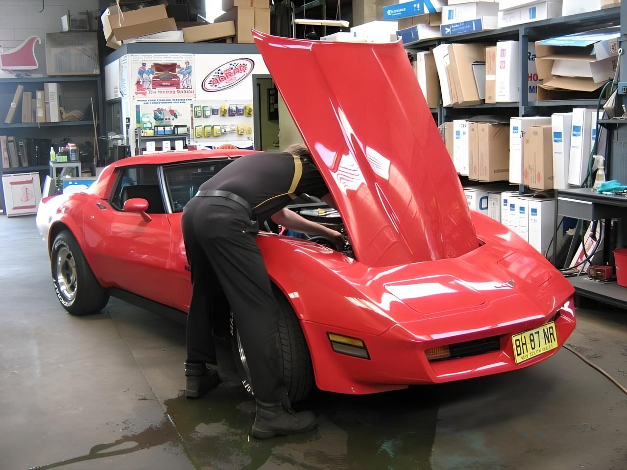 A Man is Working on a Red Corvette With the Hood Up — Neilsen's Radiator Service in Toowoomba City, QLD