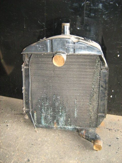 An Old Radiator is Sitting on the Ground in Front of a Black Wall — Neilsen's Radiator Service in Plainlands, QLD