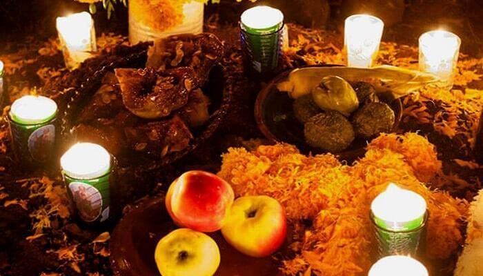 Una mesa con velas, manzanas y frutas encima.