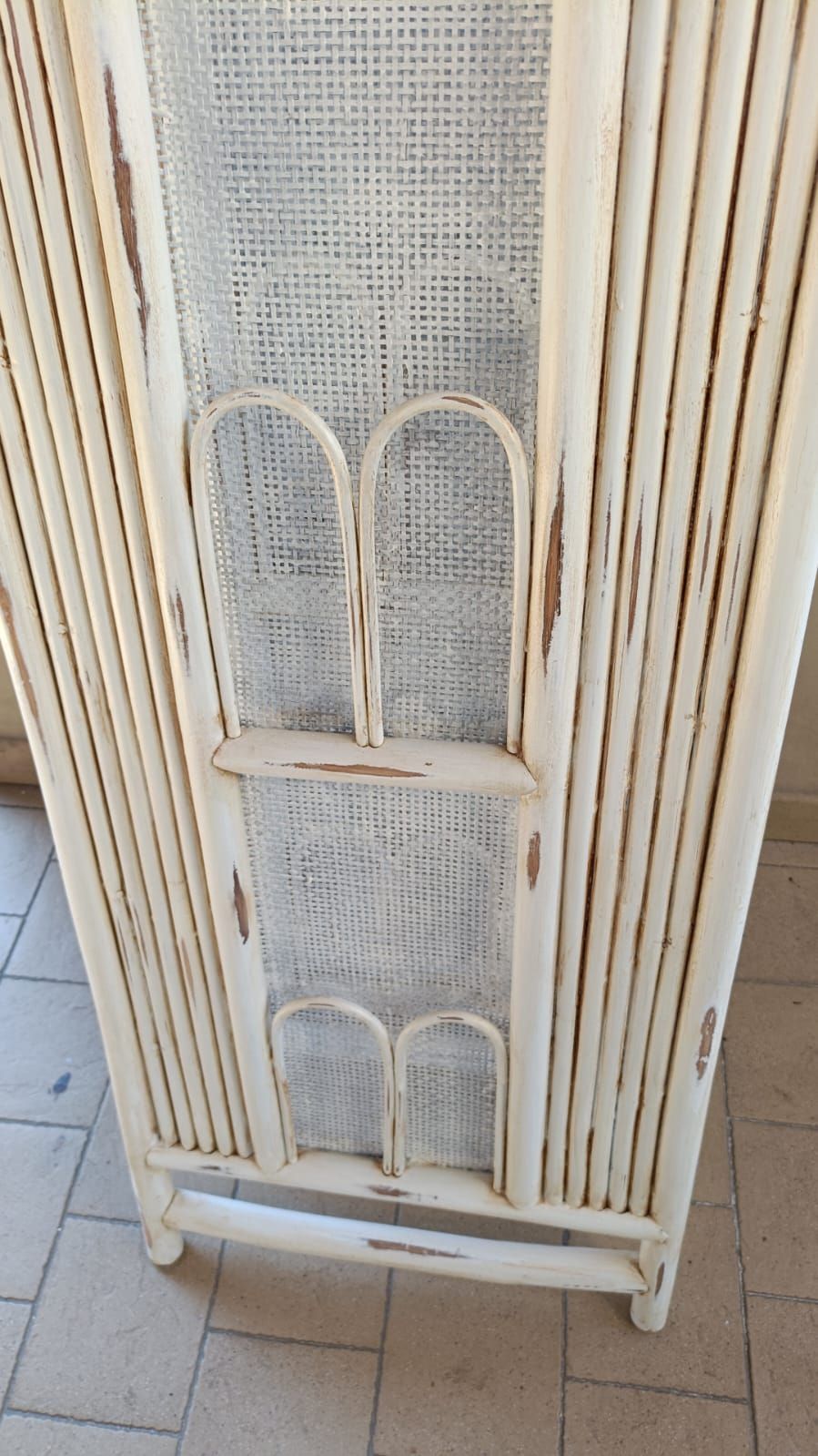 Separè intrecciato color bianco sporco. Presenta una struttura verticale simile al bambù, con un pannello in rete al centro e archi decorativi.