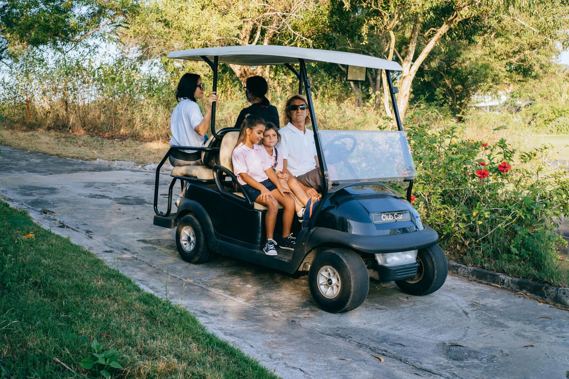 A family is riding in a golf cart down a dirt road.