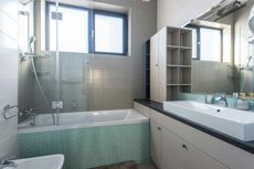 Bathroom with a white bathtub, a glass shower door, and a light-colored vanity.