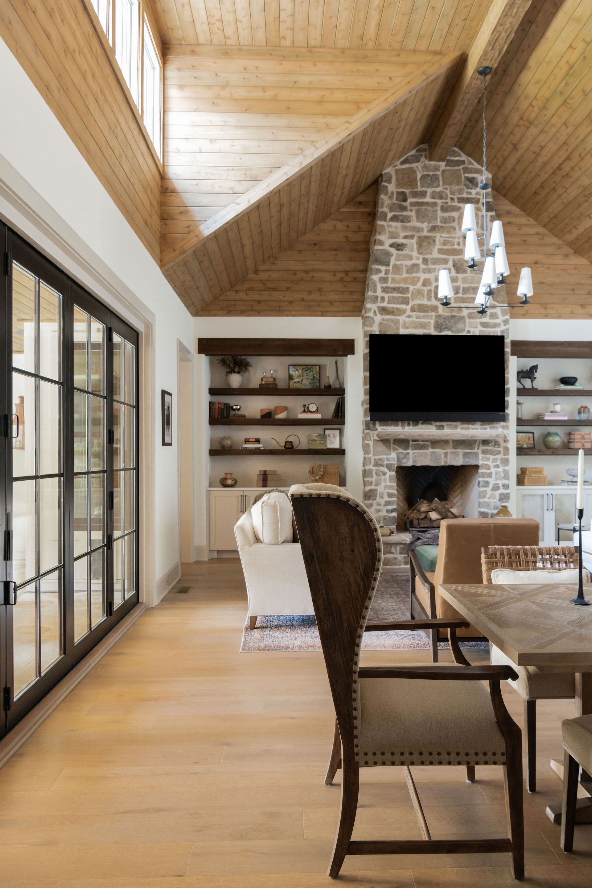 A living room with a stone fireplace , dining table and chairs.