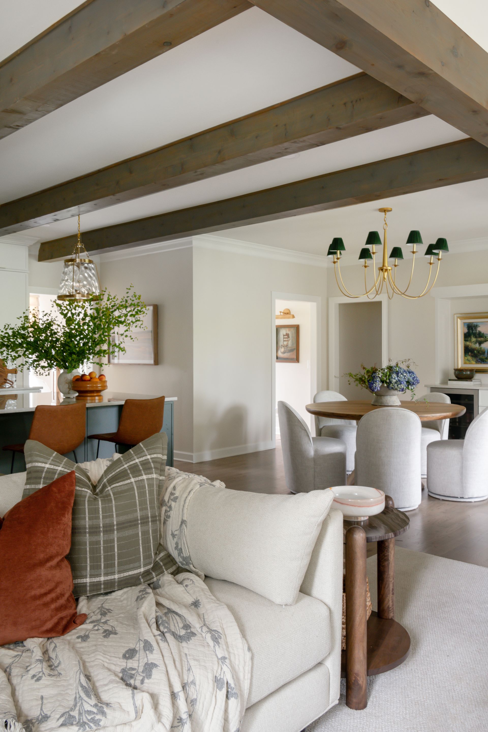 Living room with neutral walls, wooden beams, and a cozy sofa with orange and plaid pillows.