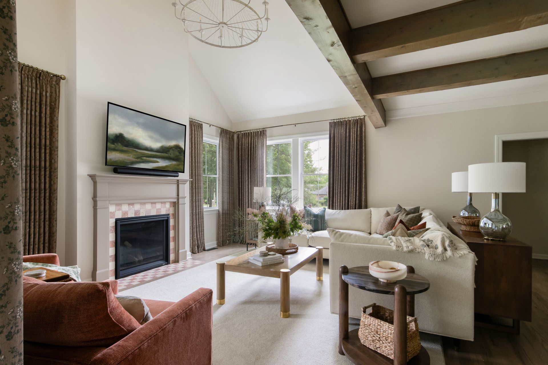 Open-concept kitchen and living room with green island, white cabinets, and wooden beams.