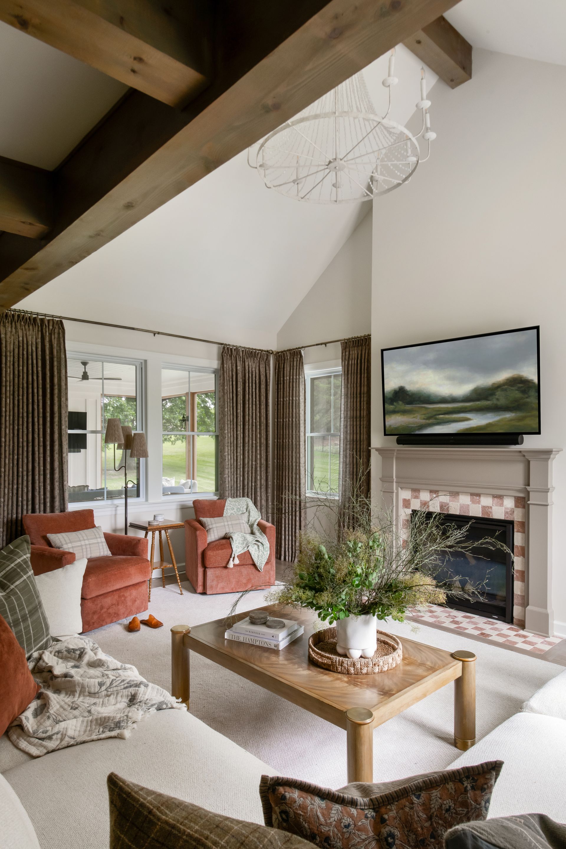Living room with vaulted ceiling, exposed beams, fireplace, and red armchairs.