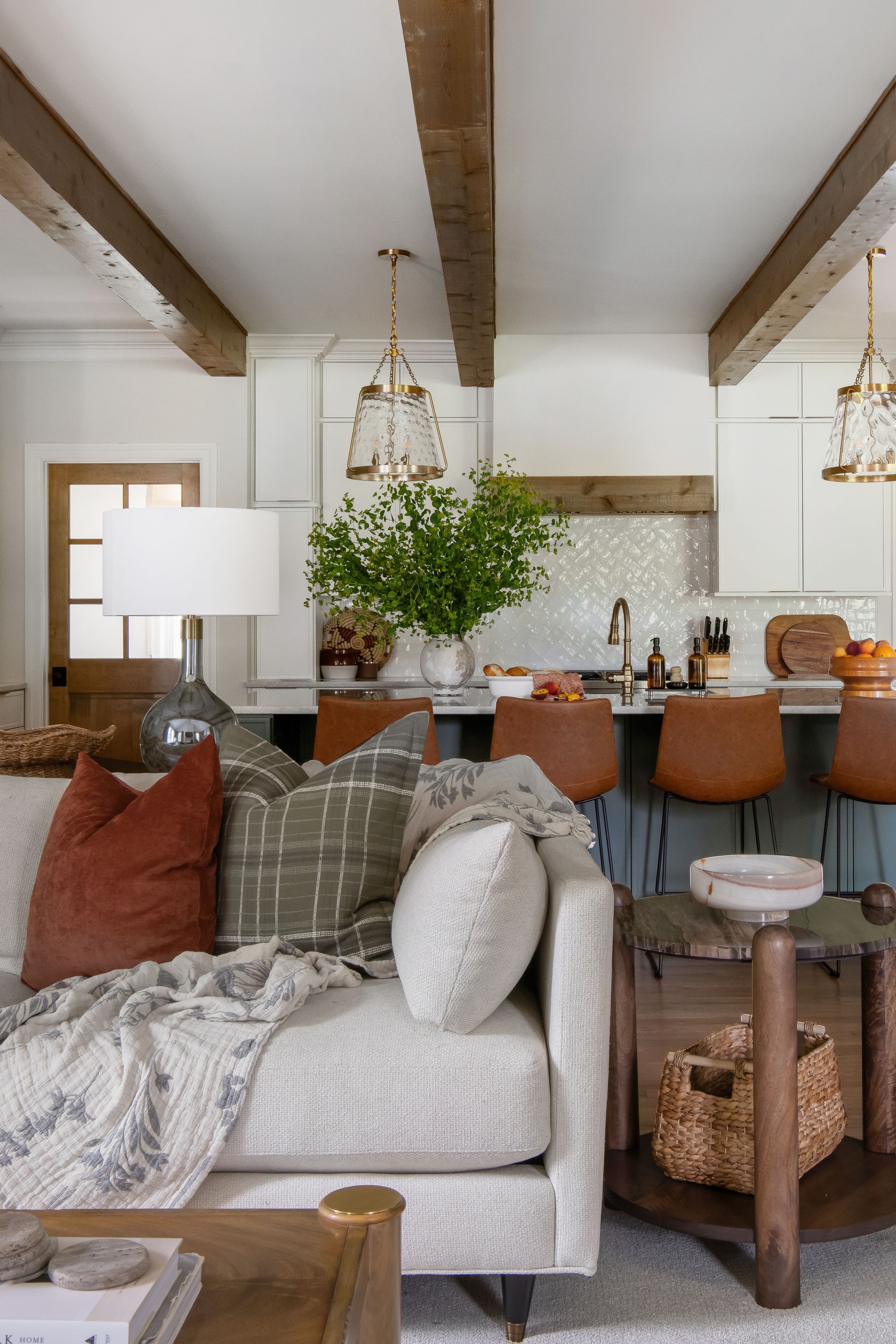 Living room with a white sofa, throw pillows, and a kitchen bar with stools.
