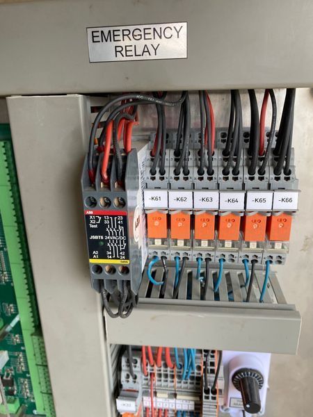 Electrical panel with various switches, wires, and circuit breakers. Yellow caution sign present.