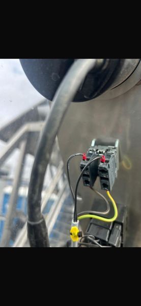 Person using a multimeter to test electrical wiring in a panel, reading 189 volts.