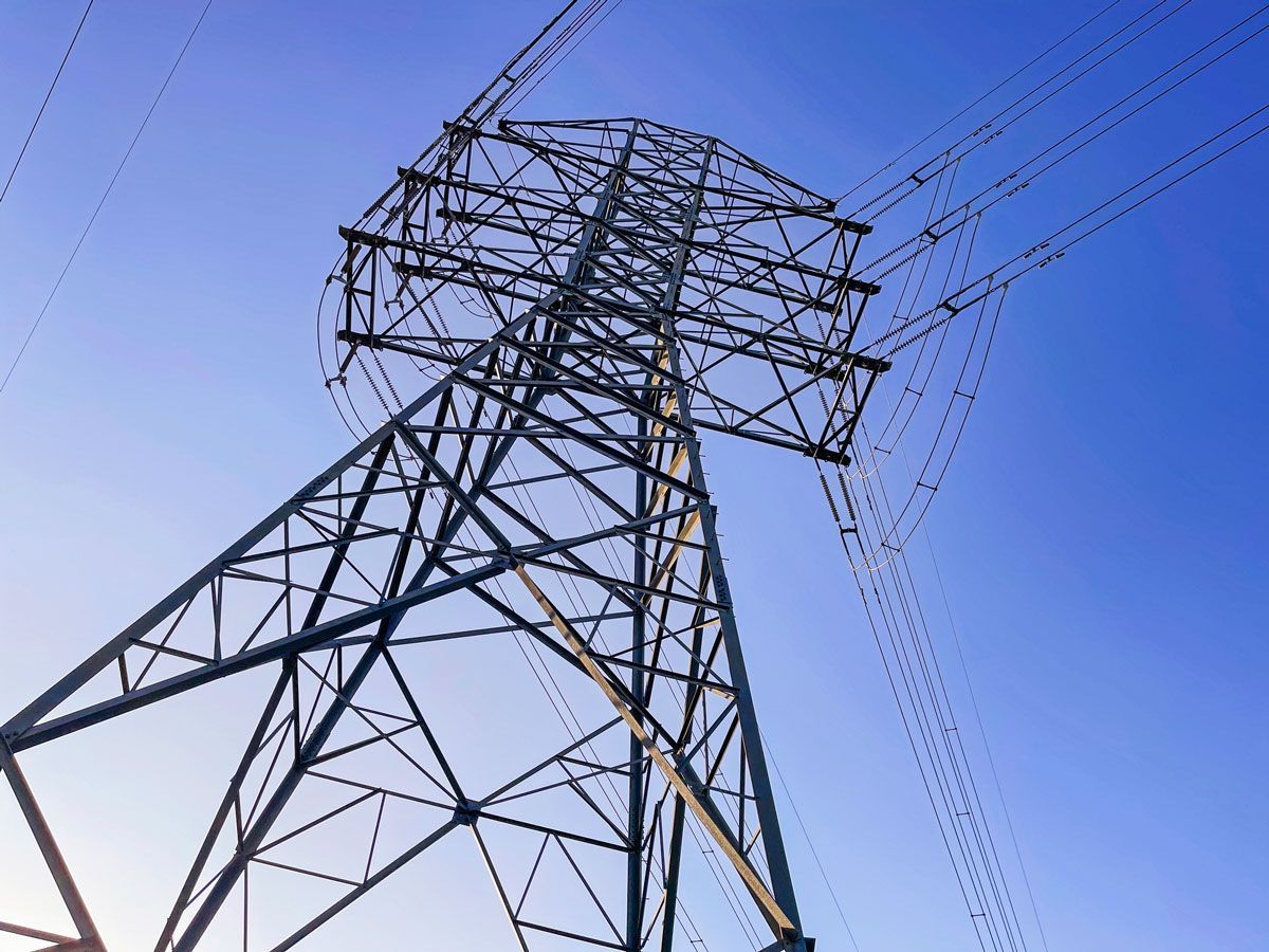 Steel electrical transmission tower against a bright blue sky.