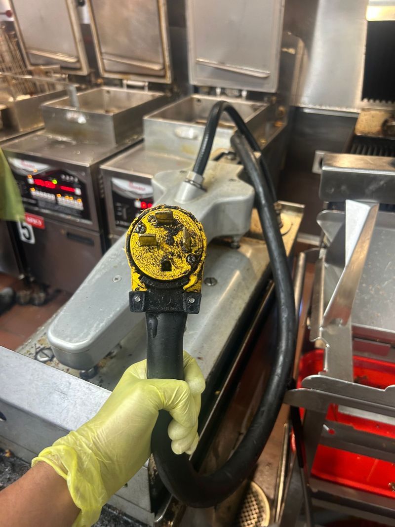 White angled electrical plug with three prongs on a pink background.