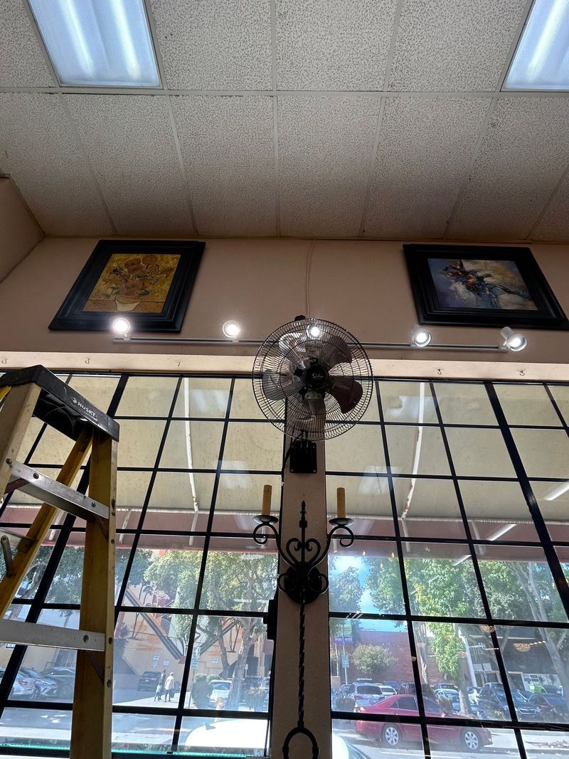 A row of four white spotlights hangs from a track on a tan ceiling. Ductwork and air vent are visible.