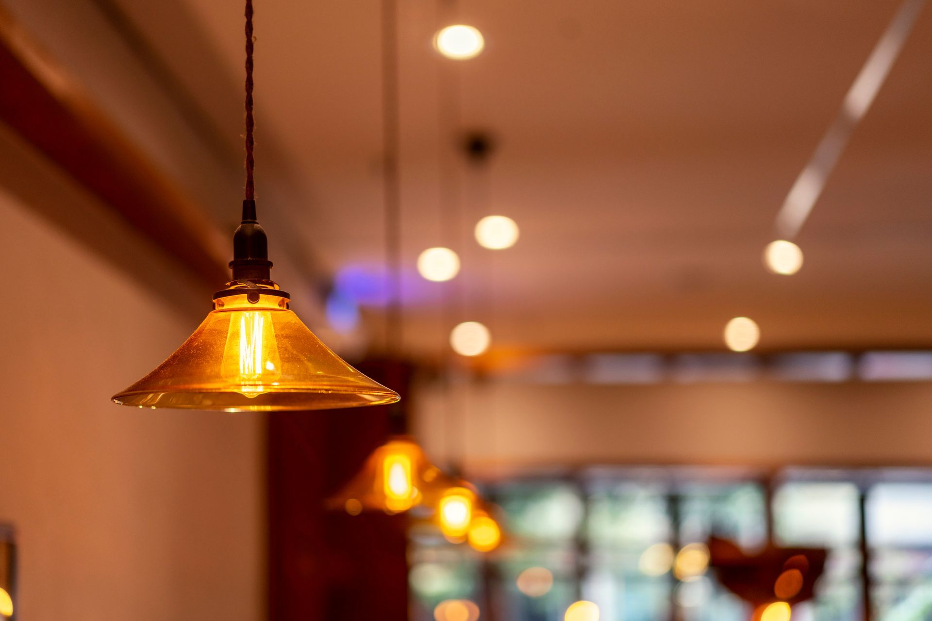 Golden pendant light with several other lights in the background, a warm-toned interior.