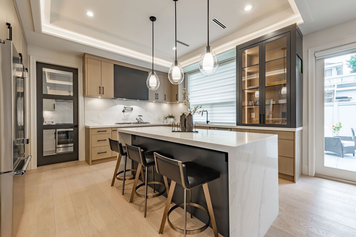 Modern kitchen with island and bar stools, light wood cabinets, and dark accents.