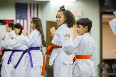 A group of children are practicing karate in a gym.