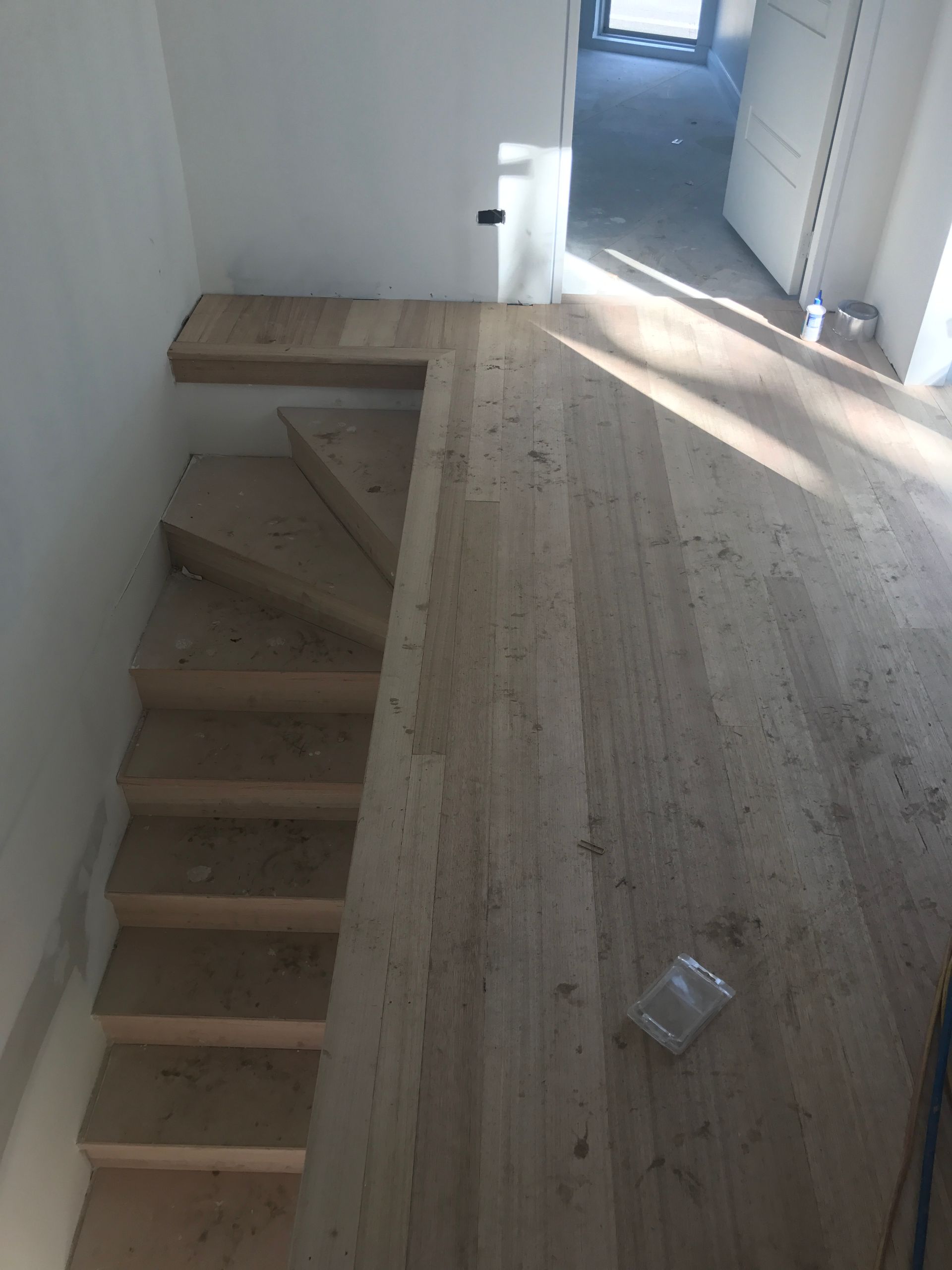 Wooden staircase and landing with unfinished flooring. Interior, top-down view.