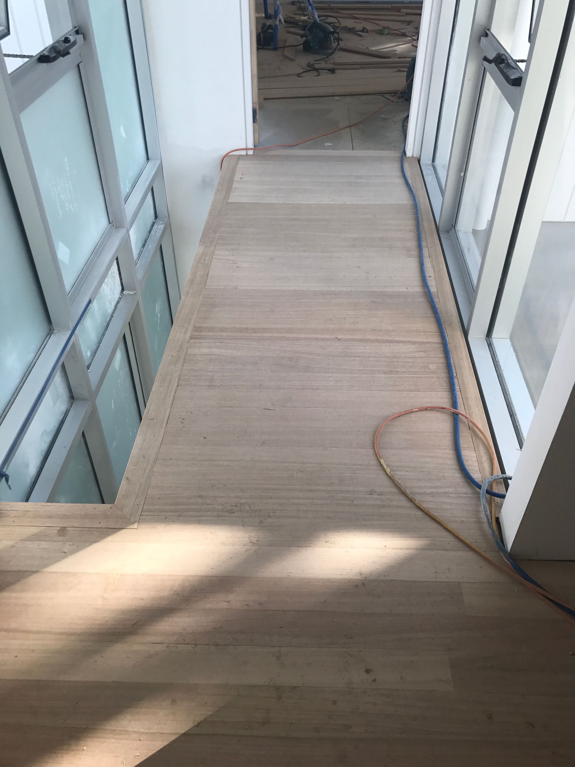 Wooden hallway with windows on each side; electrical cords run along the floor — Keystone Property Solutions In Waratah, NSW