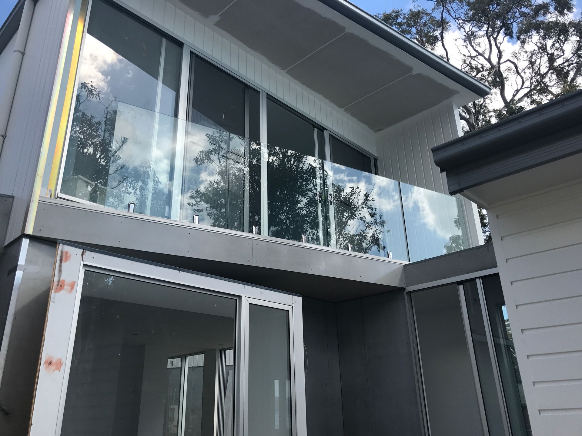 Modern house with glass balcony railing and sliding glass doors, exterior view.