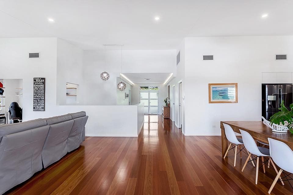 Spacious living area with wooden floor, white walls, and a dining table with chairs.