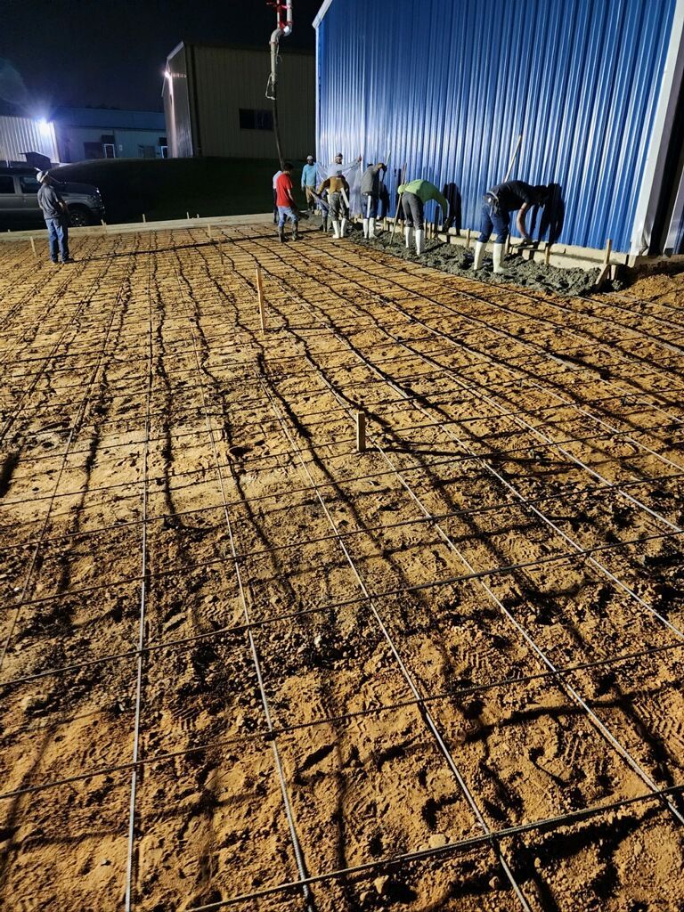 A group of people are working on a concrete driveway at night.