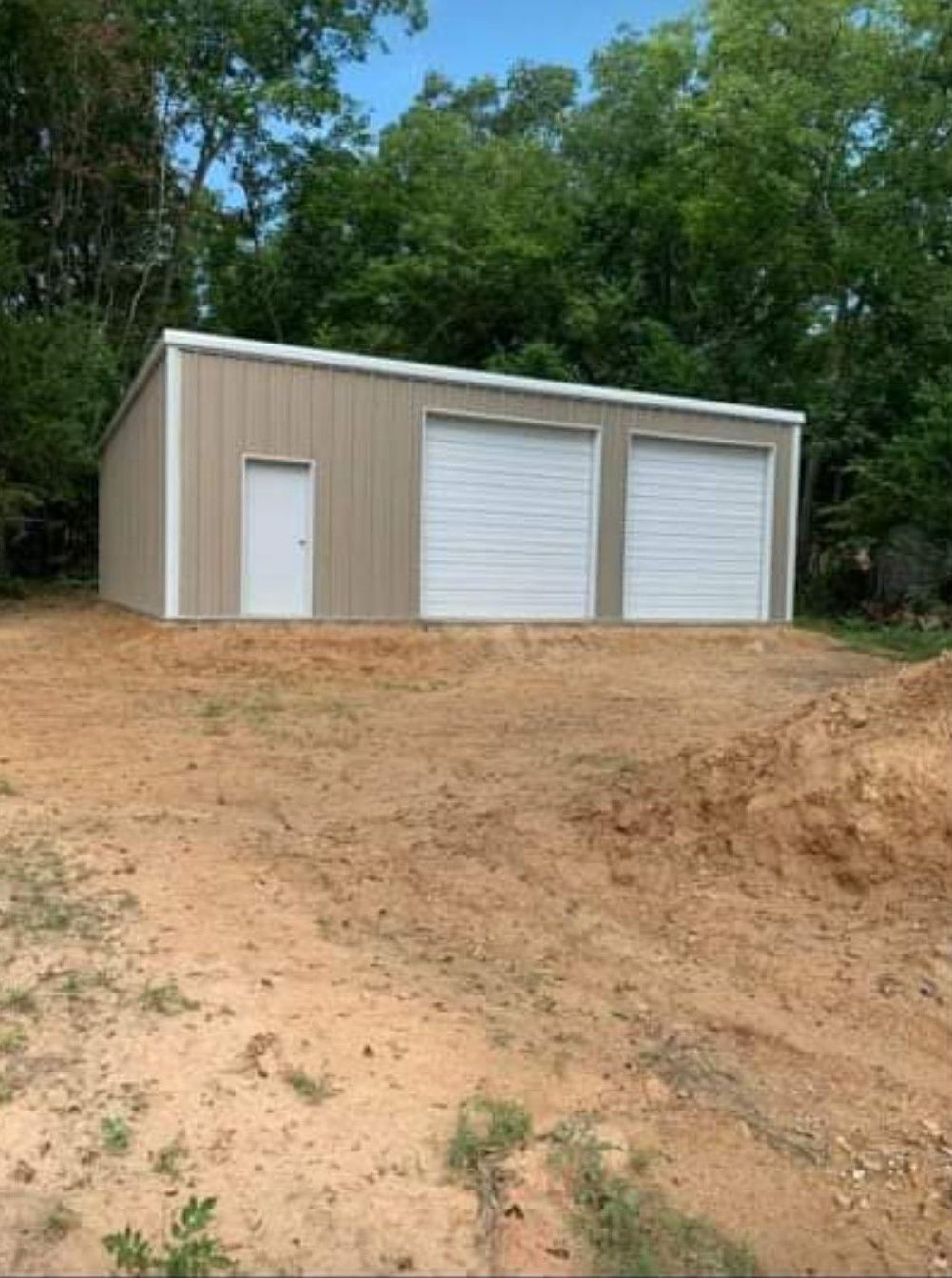 A garage with two garage doors is sitting on top of a dirt hill.