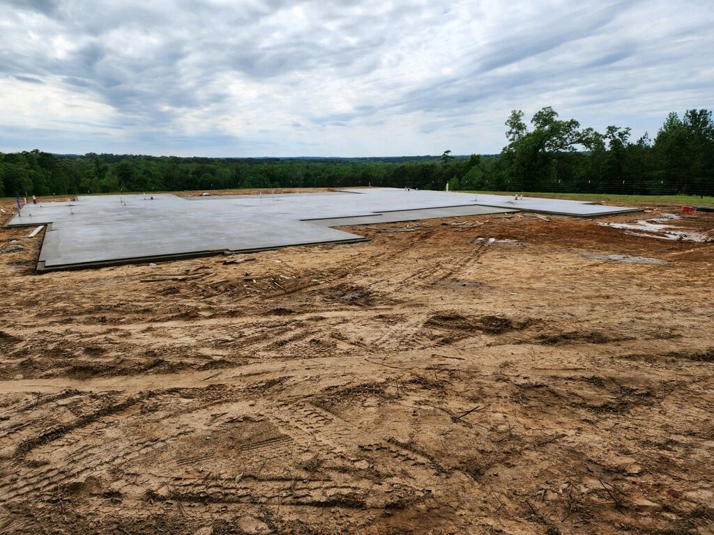 A large dirt field with a concrete slab in the middle of it.