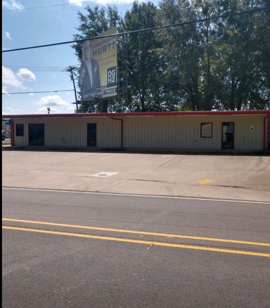 A white building with a red roof is next to a road