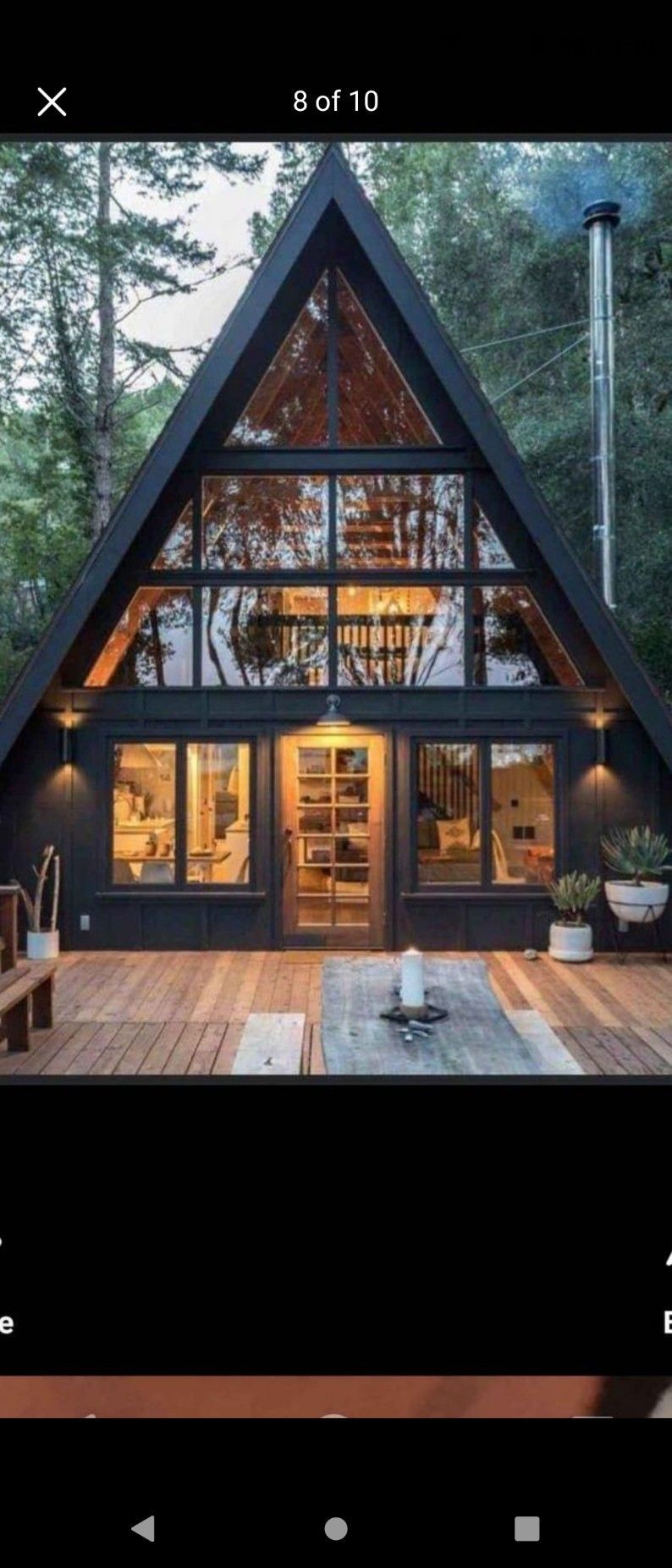 A black a frame house with a lot of windows in the woods.
