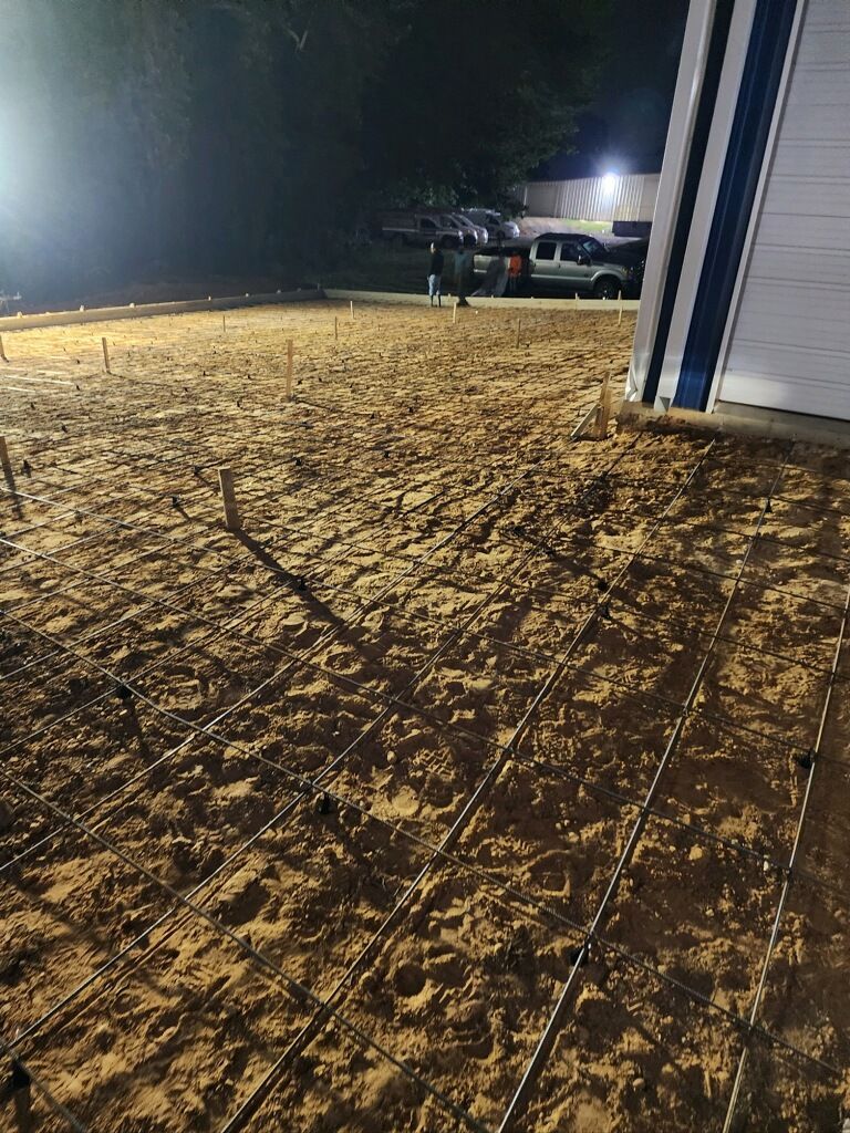 A dirt field with a building in the background at night.