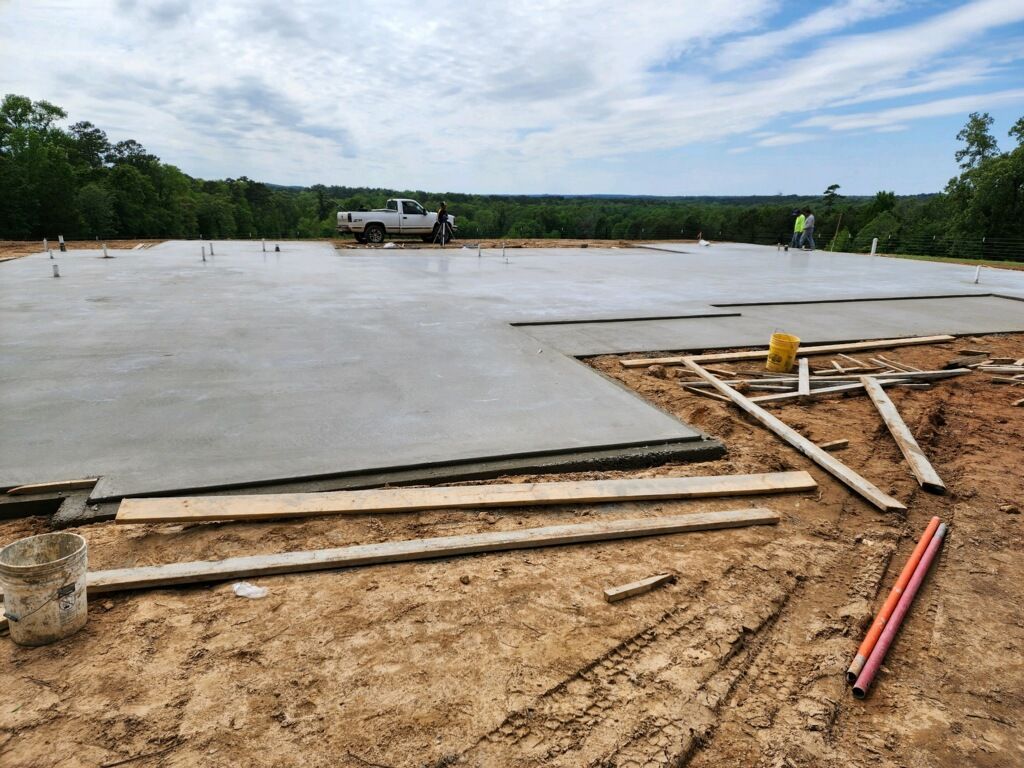 A concrete floor is being built on a dirt field.