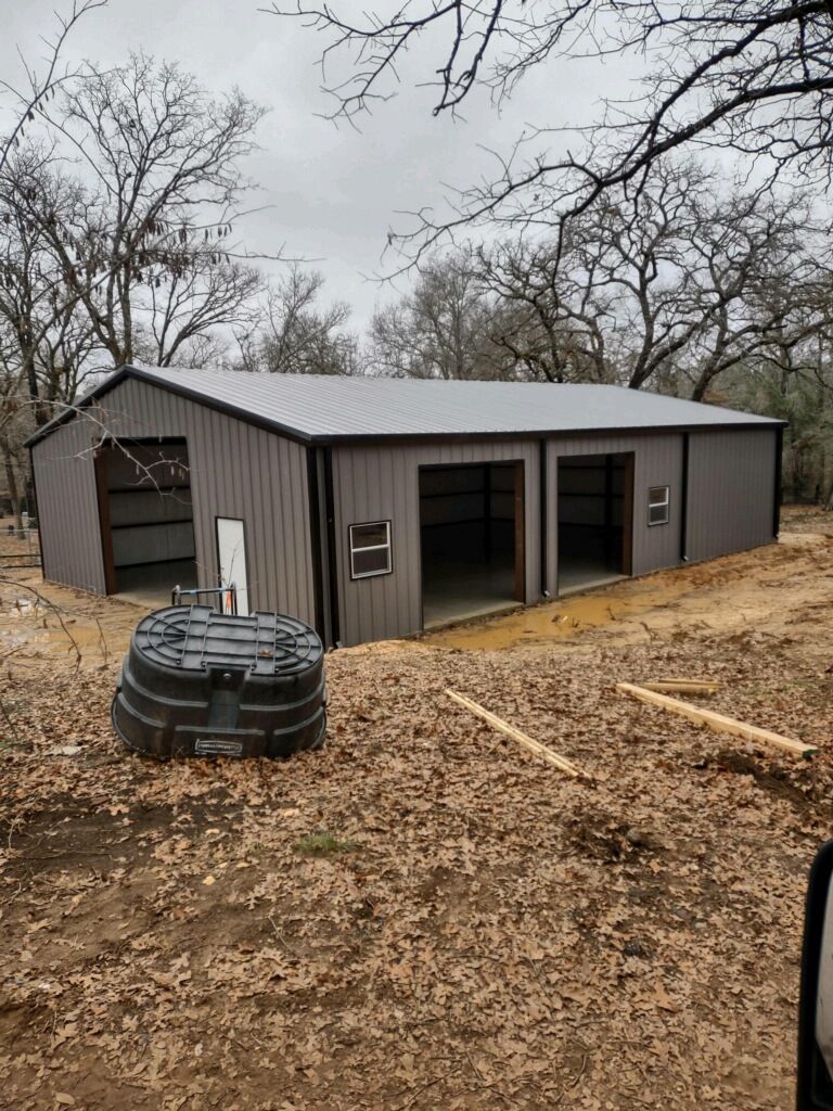 A large metal building is sitting in the middle of a field.