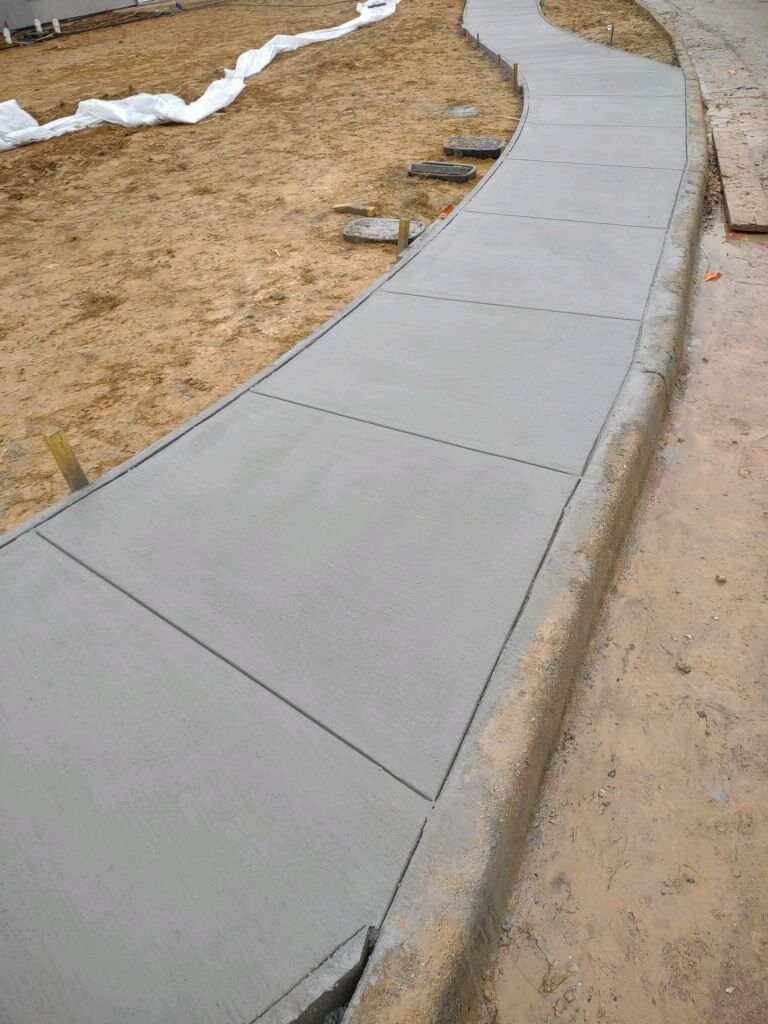 A concrete sidewalk is being built next to a dirt field.