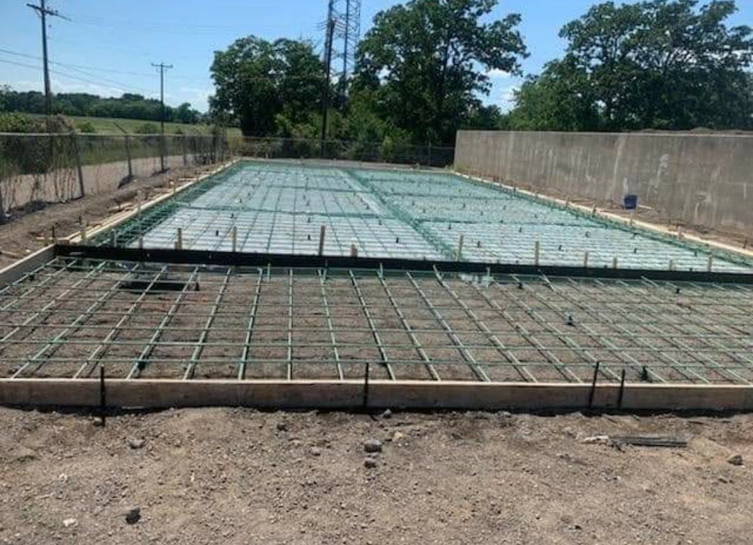 A concrete foundation is being built on a dirt field.