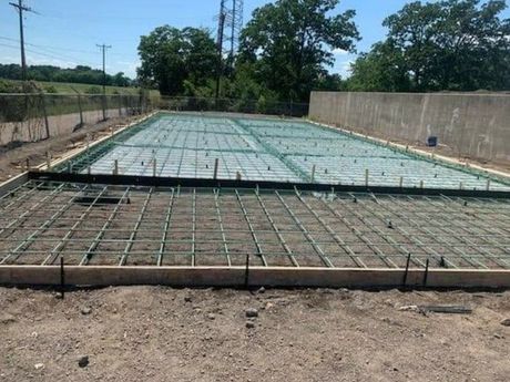 A concrete foundation is being built on a dirt field.