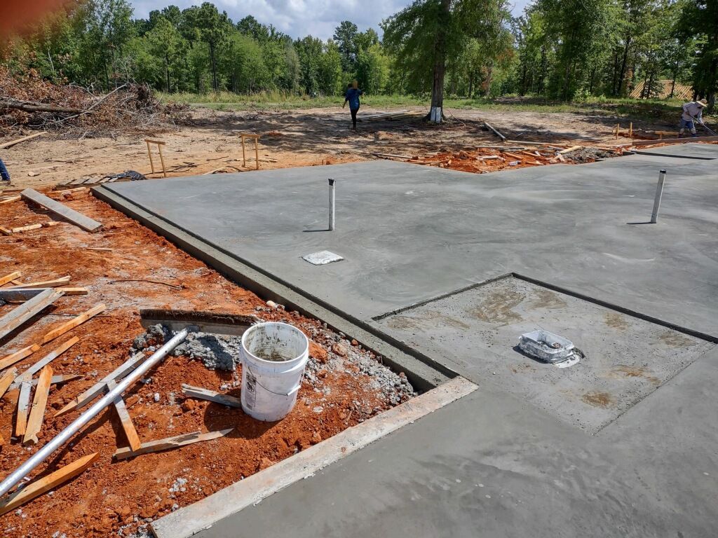 A bucket of cement is sitting on the ground in a construction site.