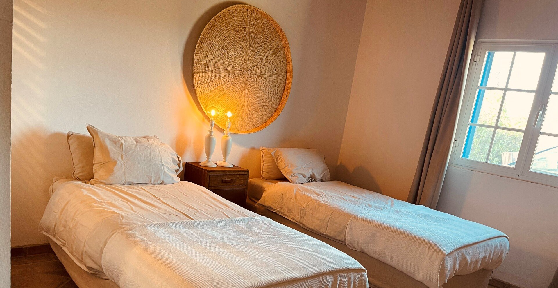 Een slaapkamer met twee eenpersoonsbedden en een raam.
