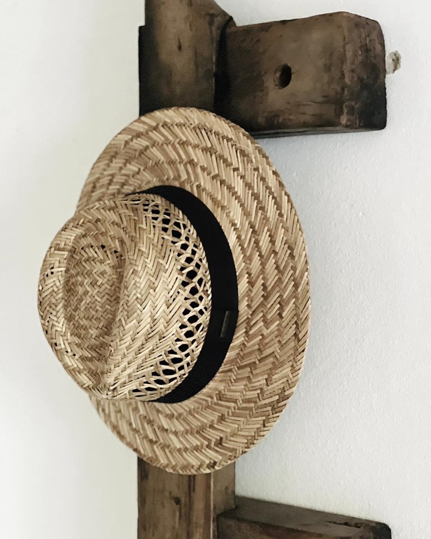 A straw hat is hanging on a wooden rack