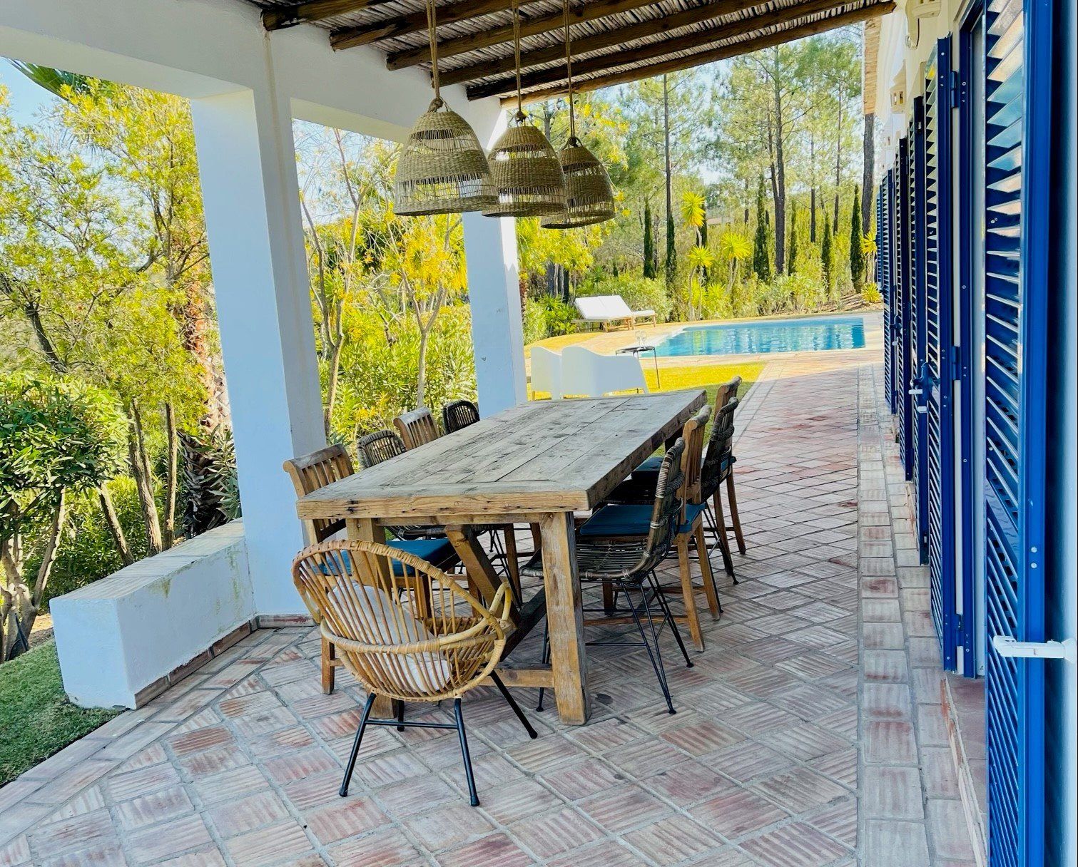 Een terras met een tafel en stoelen en een zwembad op de achtergrond.