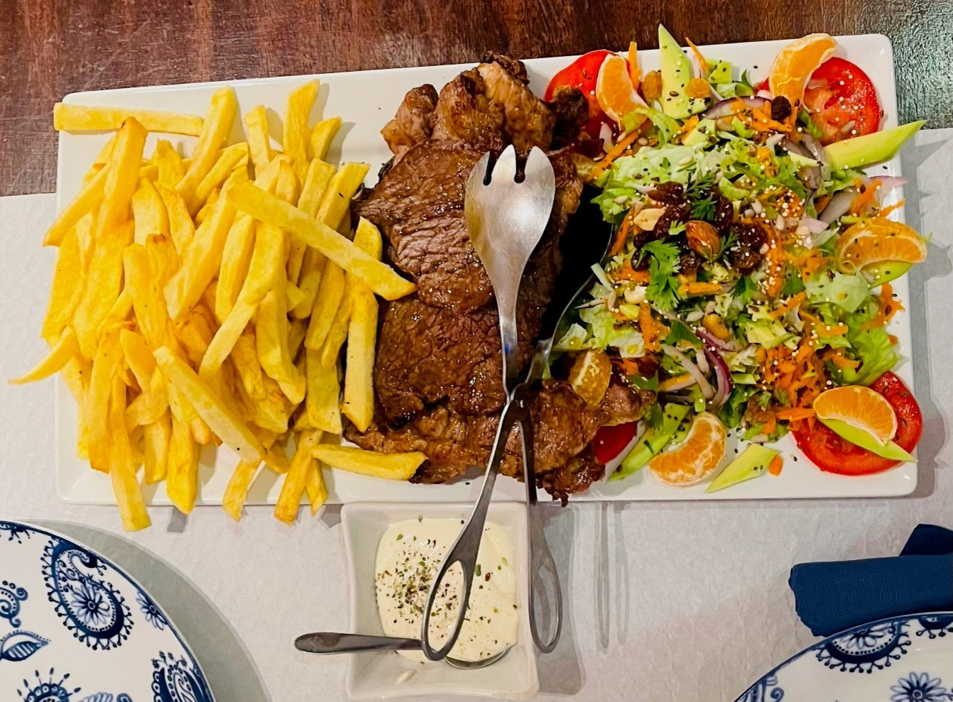 Een bord eten met frietjes en een salade op een tafel