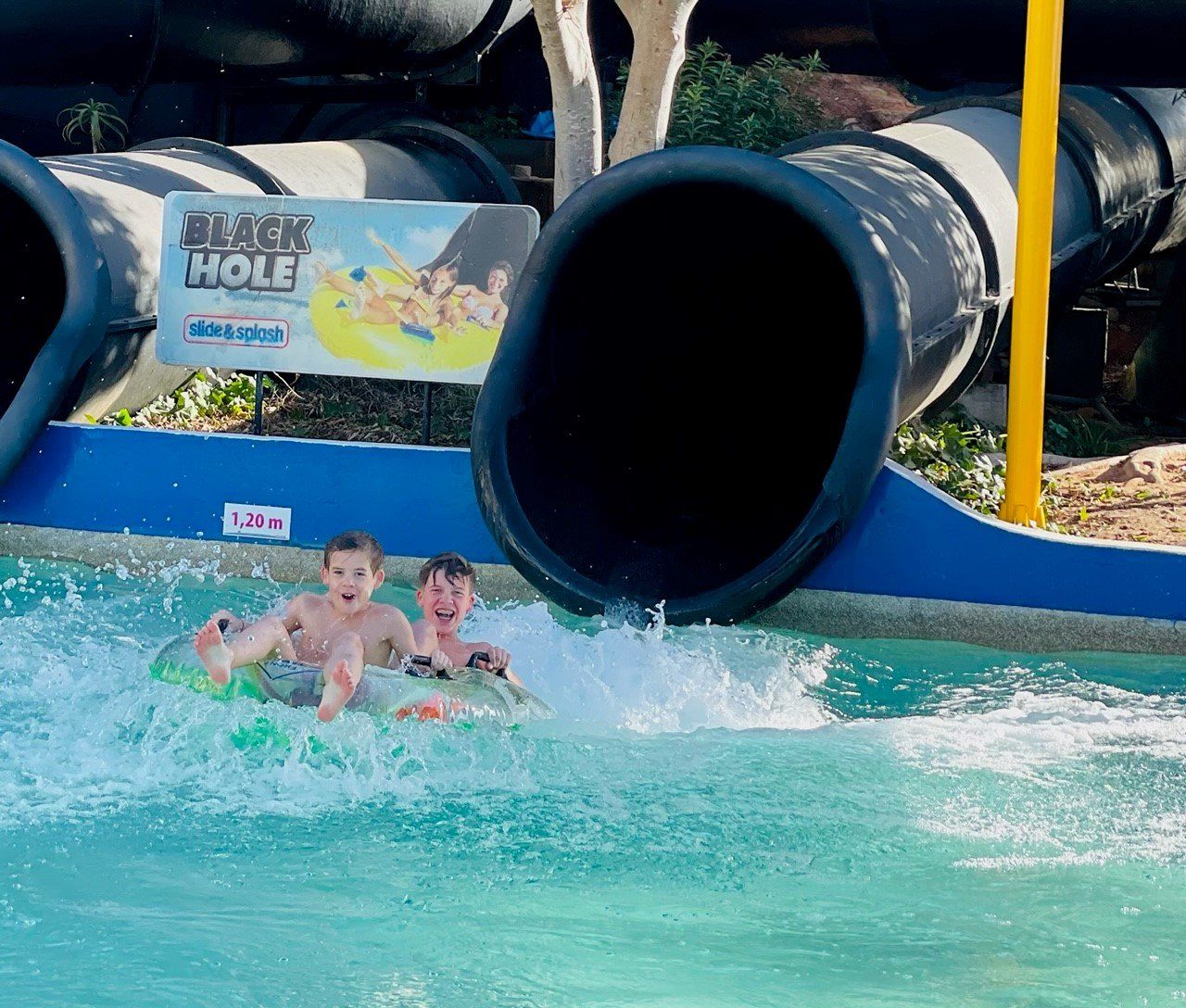 Twee jonge jongens glijden van een waterglijbaan in een waterpark.