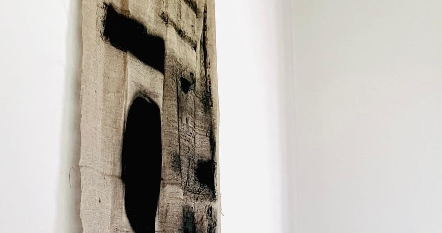 Een zwart-wit schilderij hangt aan een witte muur.