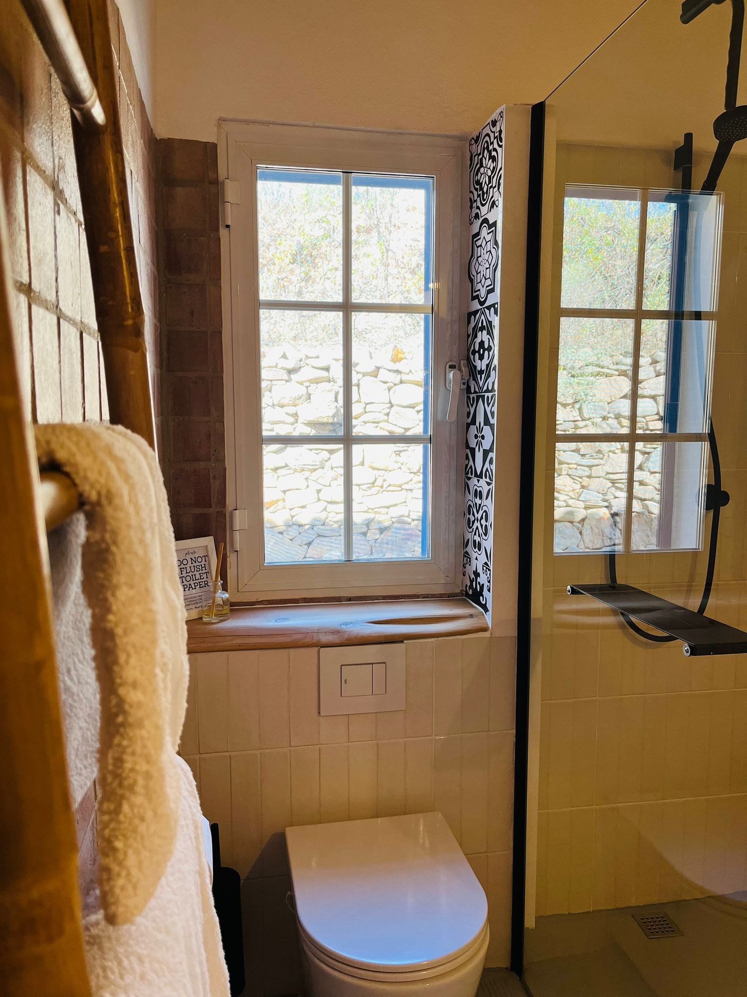 Een badkamer met toilet, douche en raam.